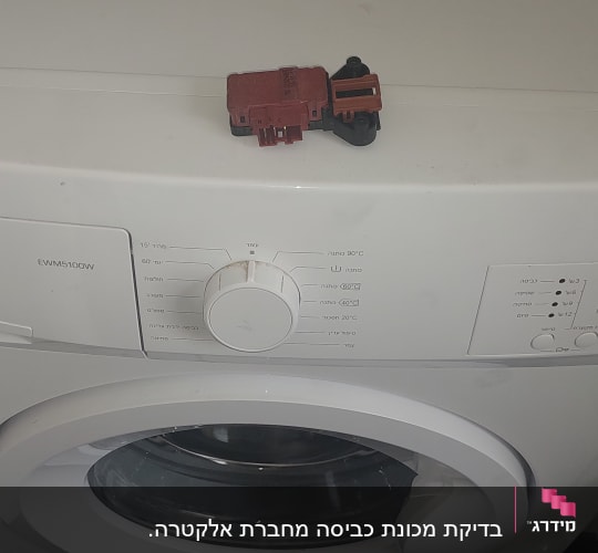 מכונת כביסה עם חלק חשמלי על המכסה